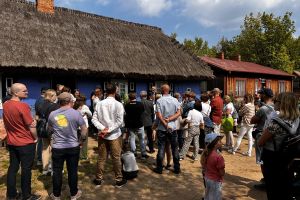 Grupa ludzi z przewodnikiem zwiedza Skansen w Maurzycach